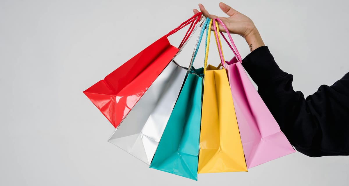 Gambar tangan kanan memegang 5 paper bag berwarna merah, perak, tosca, kuning, dan pink